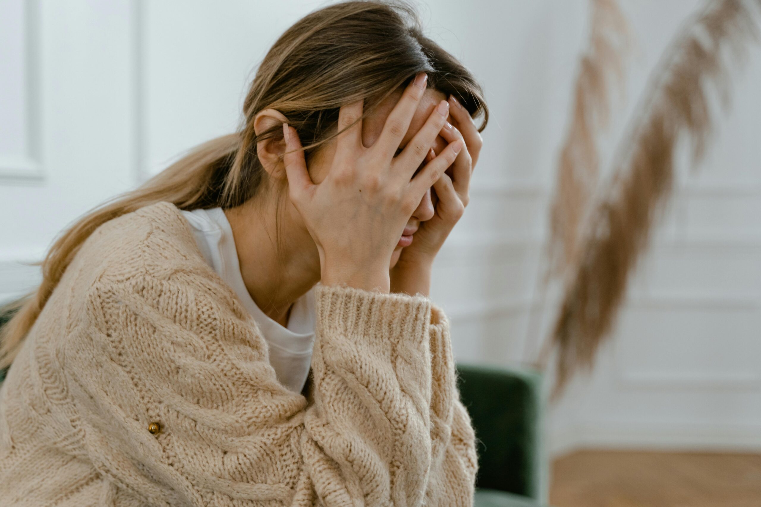 woman holding head wearing cardigan.