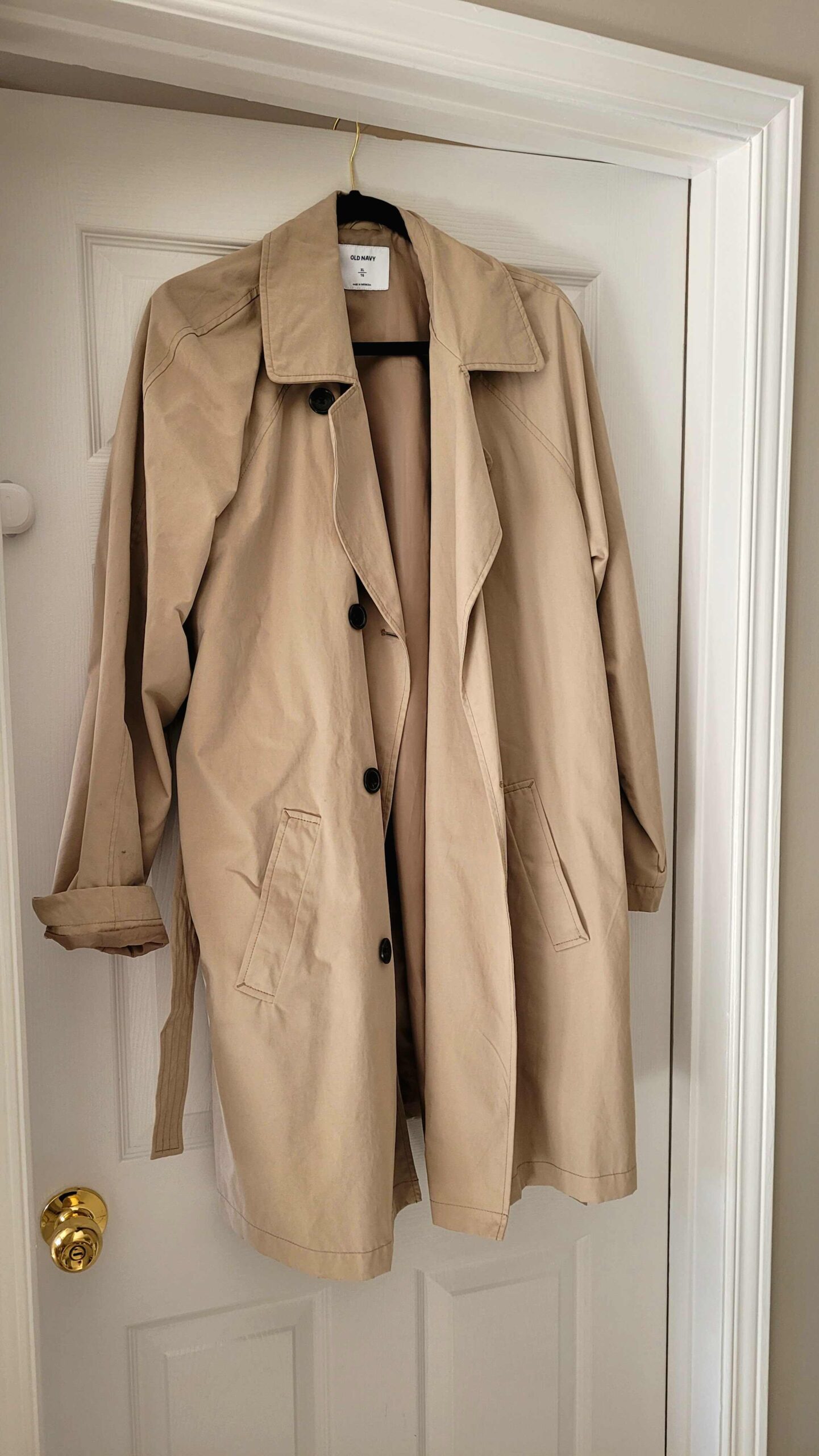 A beige trench coat hung up demonstrates UK fashion